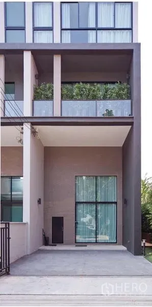 Townhouse for sale in Lak Si, Bangkok - Modern three-storey townhouse facade with covered carport and tall glass windows.