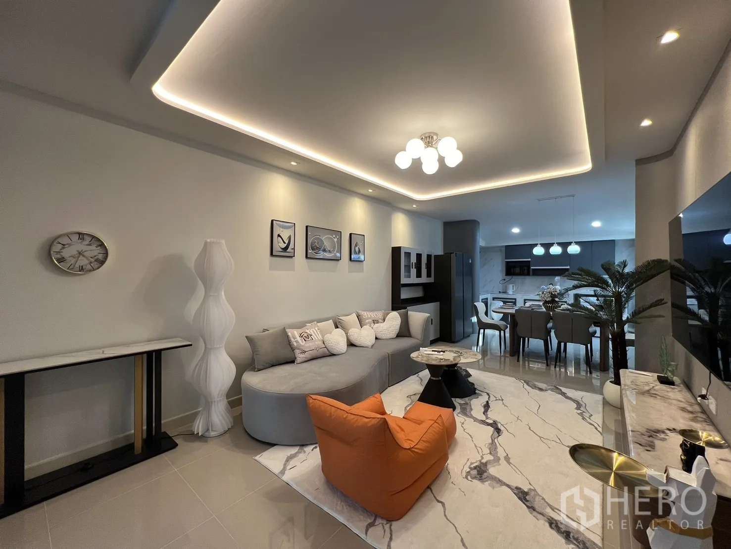 Townhouse for rent in Bang Phli, Samut Prakan - Open living space with a curved sofa, marble-pattern rug and sightline to the kitchen.