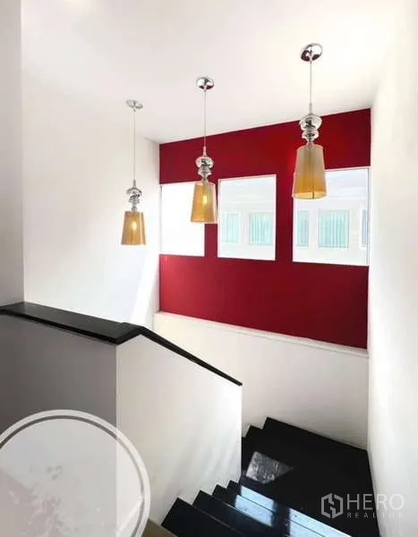 Townhouse for rent in Saphan Sung, Bangkok - Stairwell with pendant lights, red accent panel and black steps.
