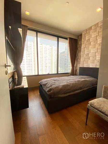 Condominium for rent in Bang Rak, Bangkok - Bright second bedroom with floor-to-ceiling window and city view.