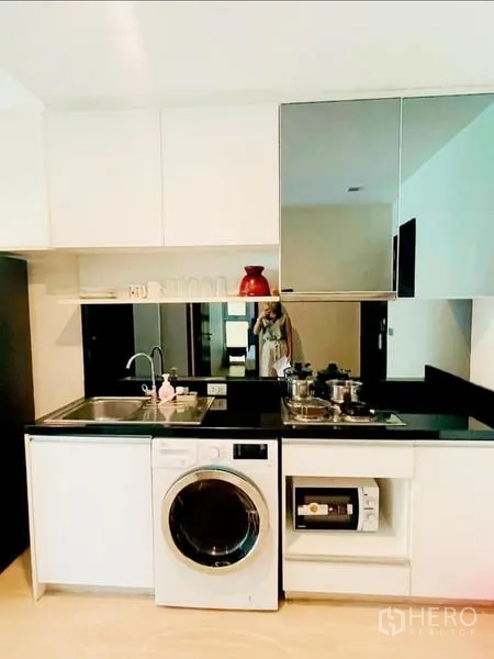 Condominium for rent - Kitchenette with sink, hob, washing machine, and mirrored cabinets.