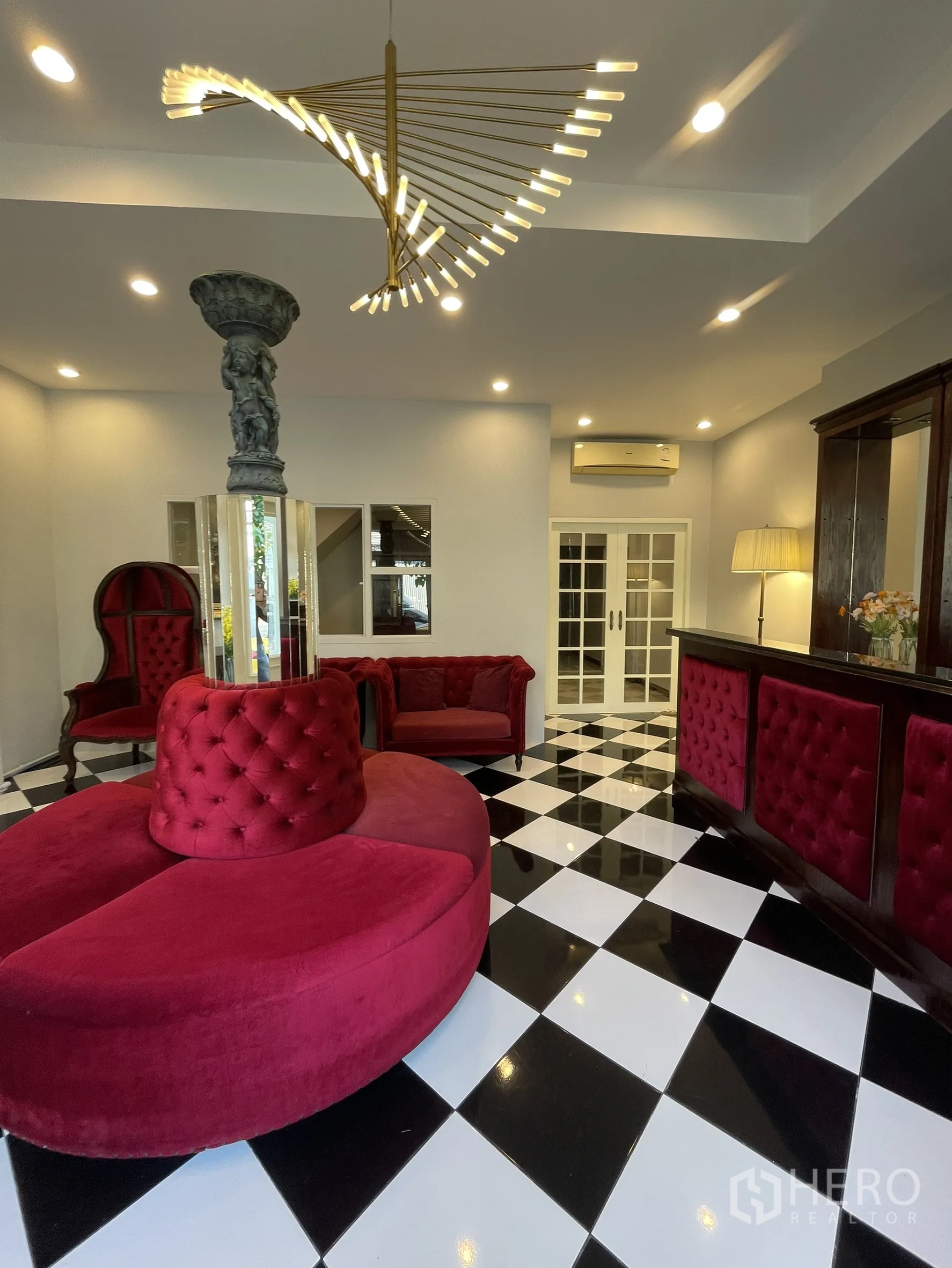 Shophouse for rent in Bang Kapi, Bangkok - Reception lounge featuring spiral chandelier, red sofas and a checkerboard floor.