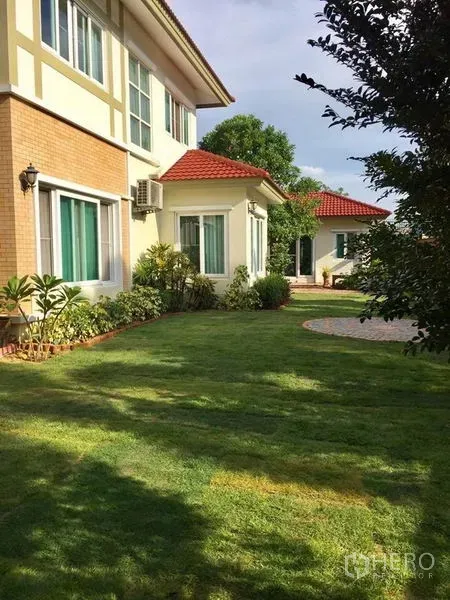 Detached House for sale in Pak Kret, Nonthaburi - Side view of the home with red-tile roofs and expansive landscaped lawn.