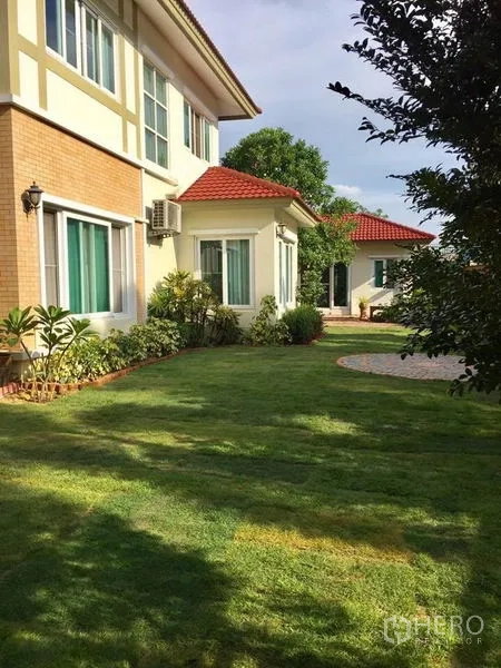Detached House for sale in Pak Kret, Nonthaburi - Side view of the home with red-tile roofs and expansive landscaped lawn.
