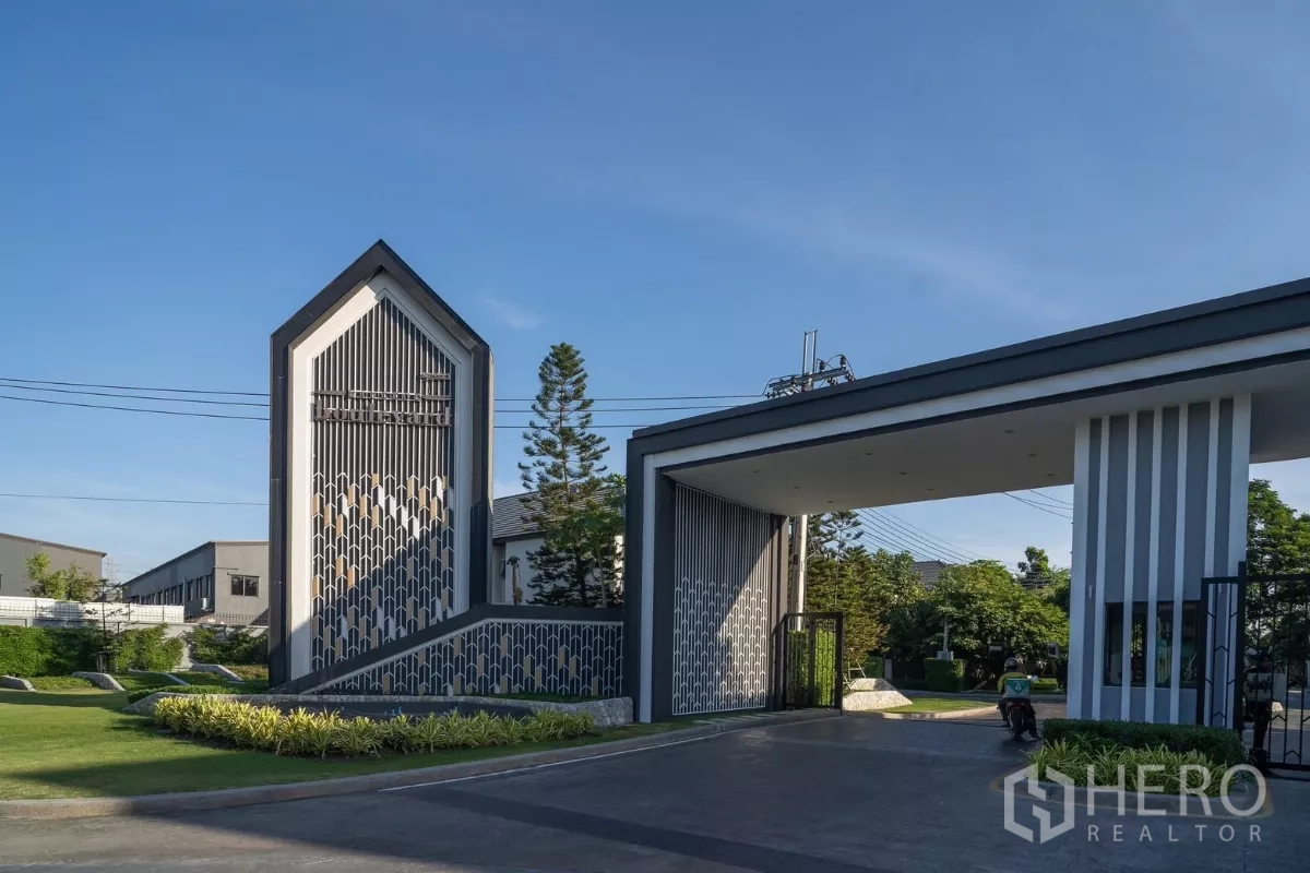 Detached House for rent in Saphan Sung, Bangkok - Secure gated community entrance with guardhouse and landscaped lawn.