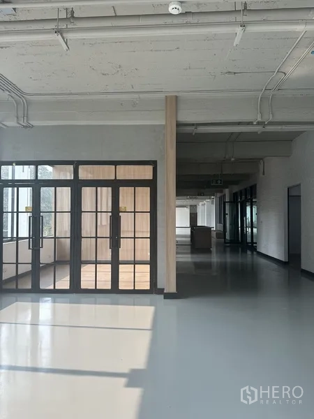 Office Space for rent - Entrance with black-framed glass doors opening to a bright corridor in the office.