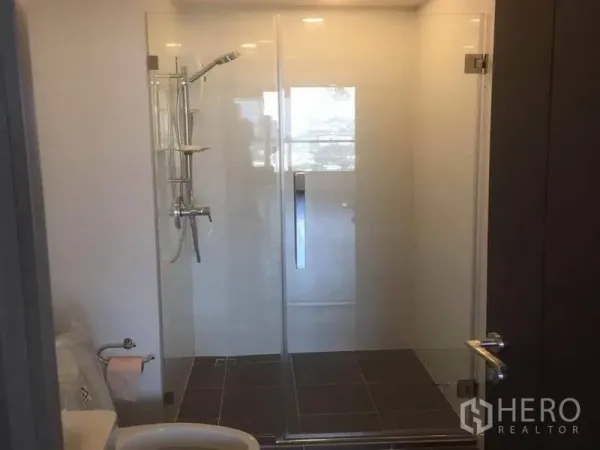 Condominium for sale in Watthana, Bangkok - Modern bathroom with glass-enclosed shower and white sanitary ware.