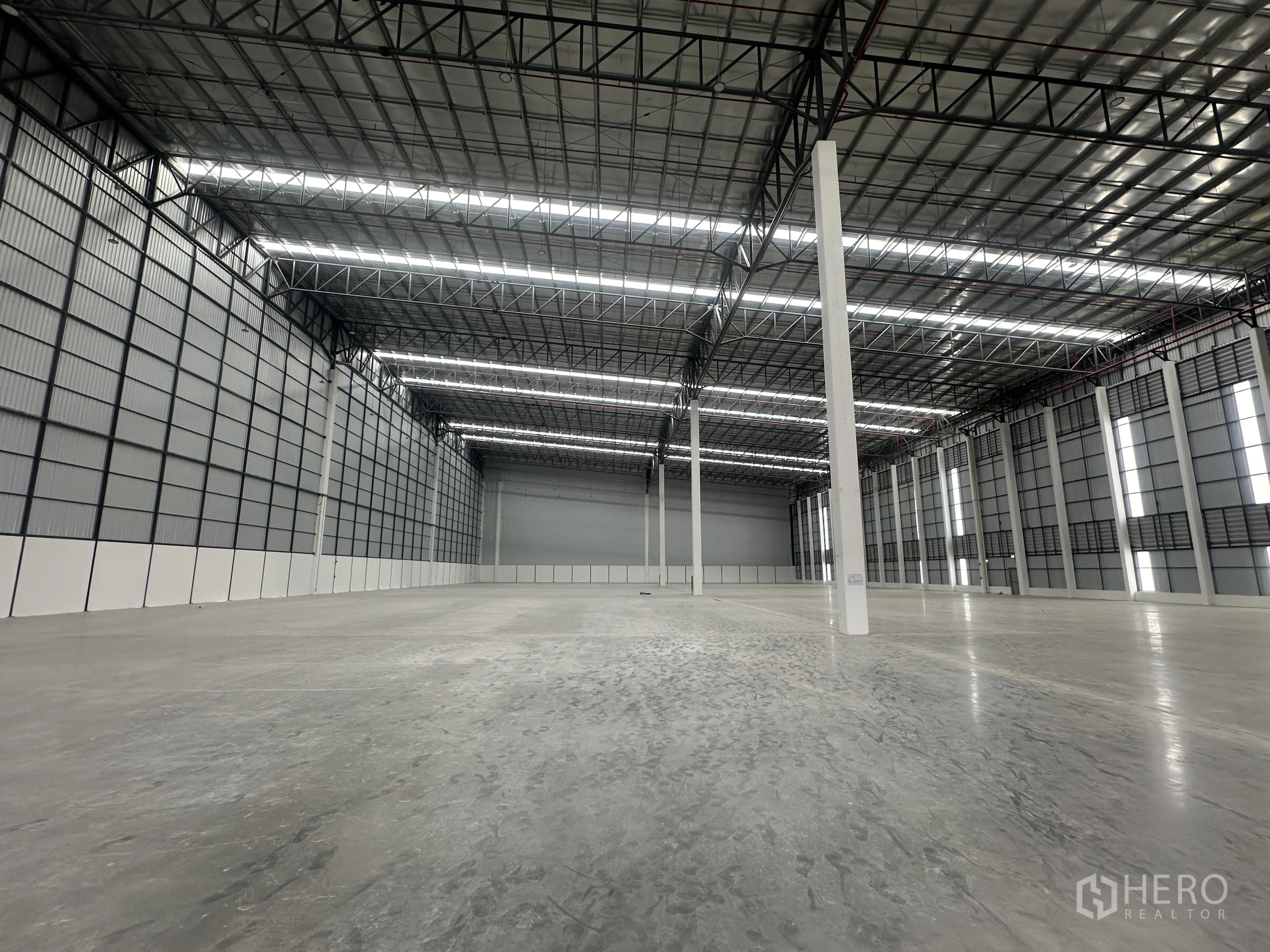 Factory for rent in Bang Phli, Samut Prakan - Expansive factory floor with polished concrete, high steel truss roof and bright strip lighting.