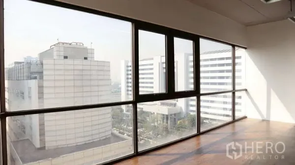 办公空间 出租 - 落地窗办公室俯瞰现代建筑与城市景观，木地板采光充足。