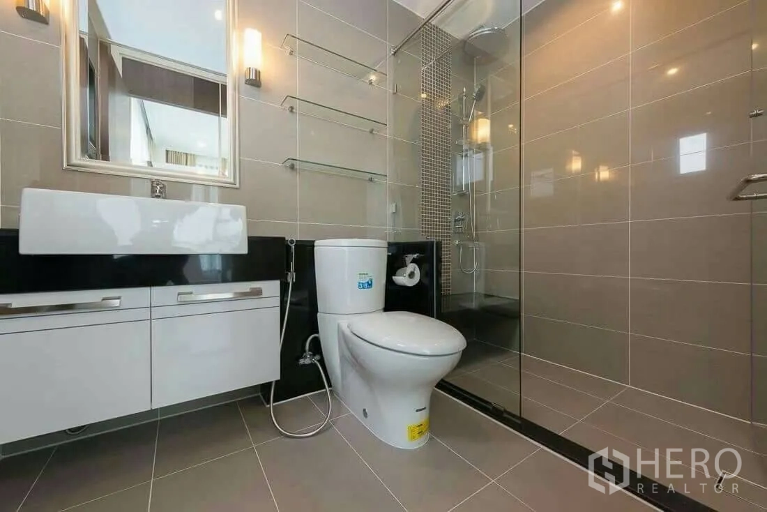 Condominium for rent in Sathon, Bangkok - Modern bathroom with glass‑enclosed shower, wall tiles and vanity cabinet.