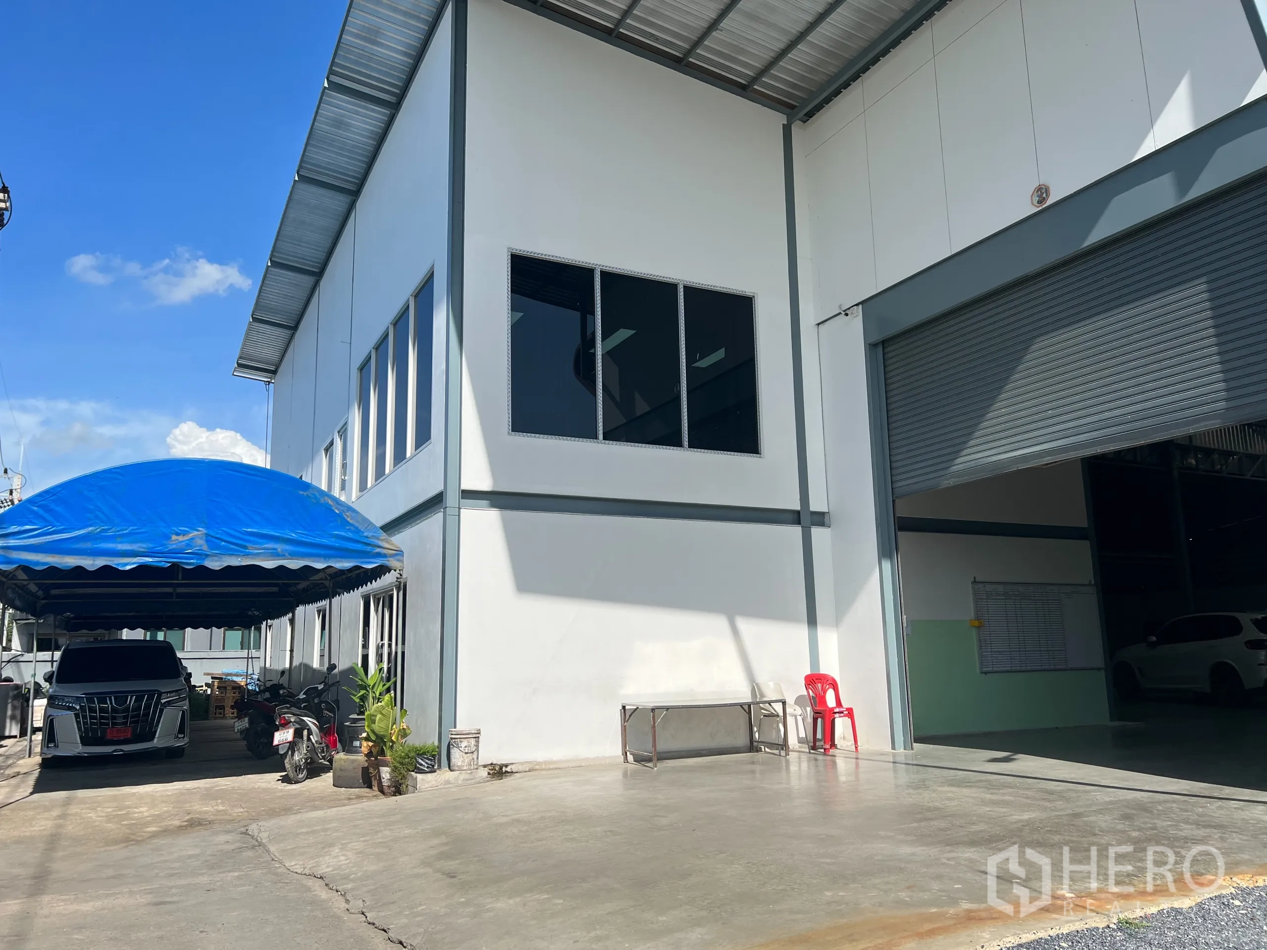 货栈 出售在Lam Luk Ka, Pathum Thani - 前院带蓝色车棚、办公室窗户及大型卷帘门。