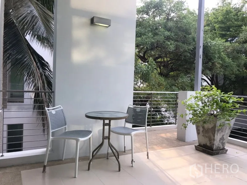 ทาวน์เฮาส์ ให้เช่าหรือขายในChatuchak, Bangkok - ระเบียงพร้อมชุดโต๊ะกาแฟ เก้าอี้สองตัว และกระถางต้นไม้ มองเห็นต้นไม้ร่มรื่น