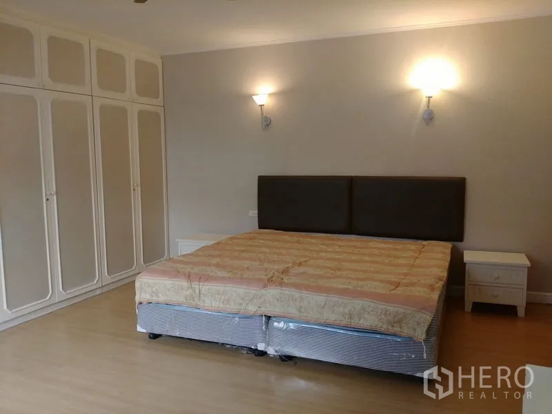 คอนโด ให้เช่าในWatthana, Bangkok - เตียงคิงไซซ์พร้อมหัวเตียงบุผ้า โคมไฟติดผนังคู่ และตู้เสื้อผ้า