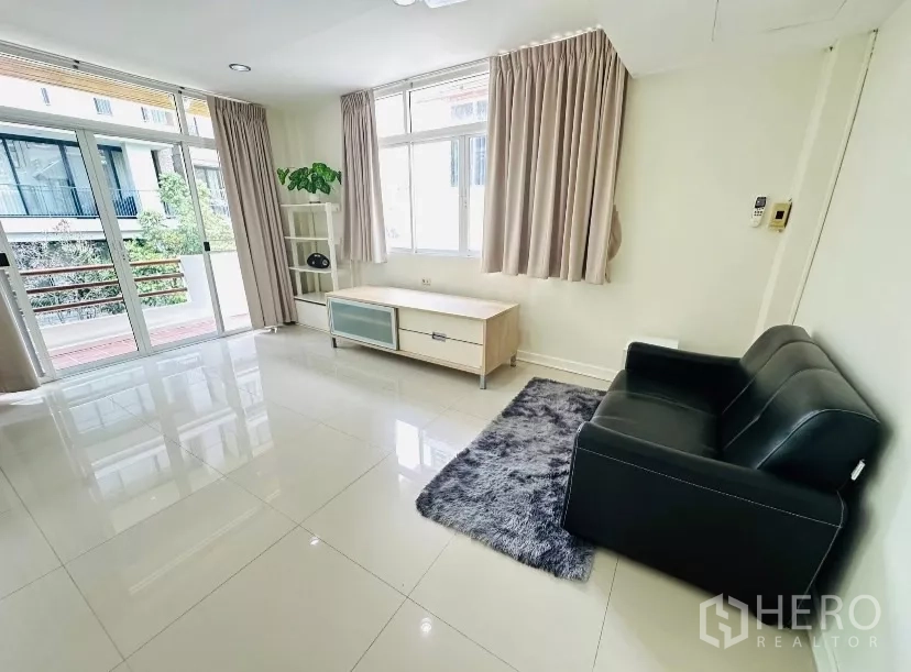 บ้าน ให้เช่า - มุมนั่งเล่นอบอุ่น โซฟาหนังขนาดเล็ก พรม และประตูกระจกออกระเบียง.