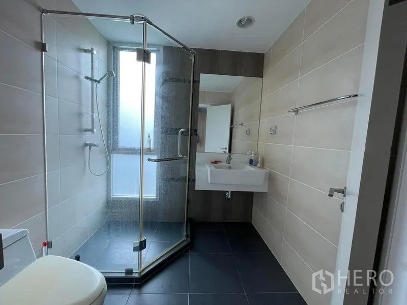 公寓 出售在Sathon, Bangkok - 现代浴室，设玻璃淋浴房、米色墙砖与悬挂式洗手台。