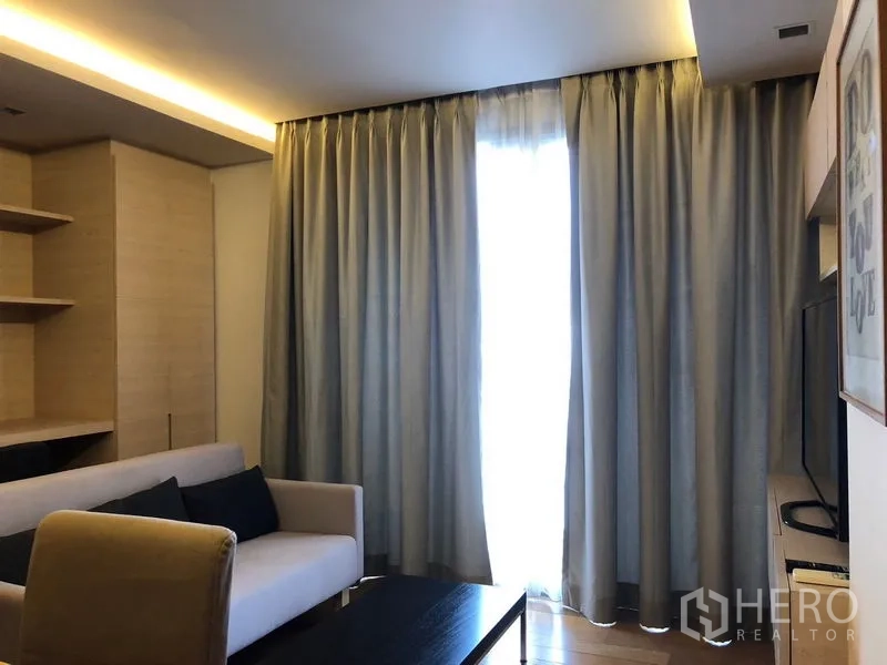 คอนโด ให้เช่าในWatthana, Bangkok - ห้องนั่งเล่นอบอุ่น โซฟา ผ้าม่านเต็มความสูง และไฟซ่อนสวยงาม