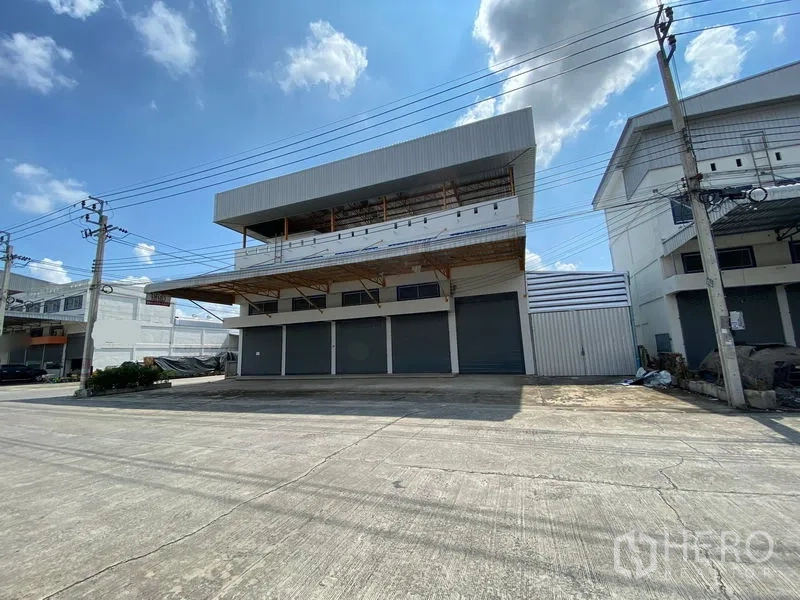 货栈 出租或出售在Bang Phli, Samut Prakan - 仓库外立面斜视图，带遮雨装卸雨棚及宽敞临街通道。