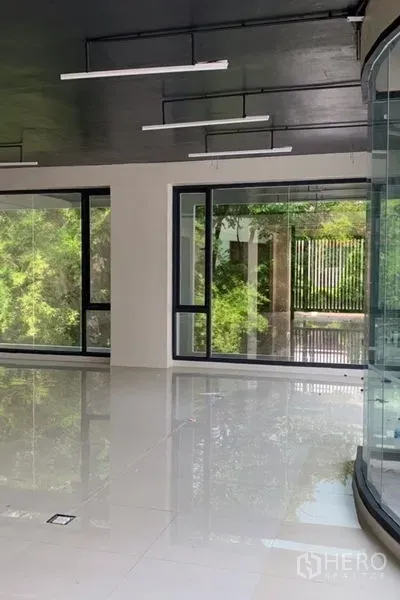 独立商业地产 出租在Khlong Toei, Bangkok - 采光充足的室内，落地窗与亮面地砖，可见花园景观。