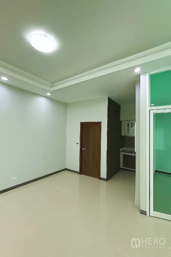 Home Office for rent in Bang Phli, Samut Prakan - Bright tiled room with recessed lights, a wooden door and a compact kitchenette corner.