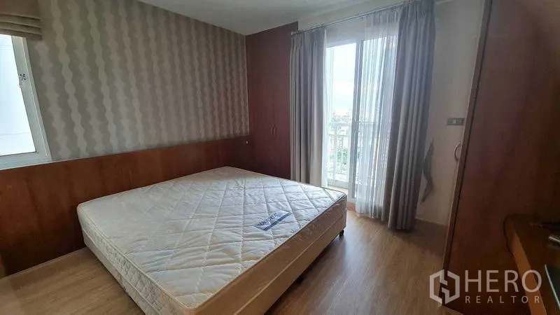 Condominium for rent or sale in Watthana, Bangkok - Main bedroom with large window and balcony access, wood paneling, and a queen bed.