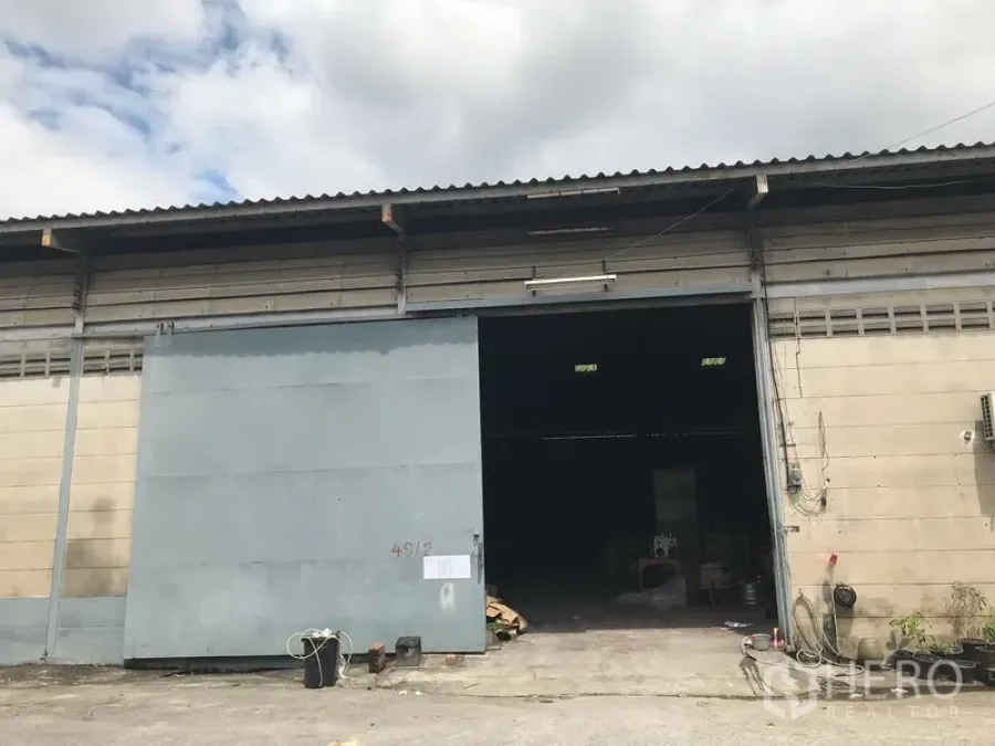 คลังสินค้า ให้เช่าในBang Phli, Samut Prakan - ด้านหน้าโกดังอุตสาหกรรมพร้อมประตูเหล็กบานเลื่อนขนาดใหญ่และพื้นที่จอดรถ