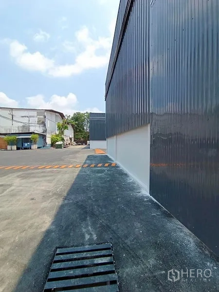 货栈 出租在Khlong Toei, Bangkok - 仓库侧边通道，灰色金属墙与排水沟、减速带