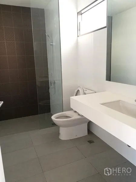 Townhouse for rent in Saphan Sung, Bangkok - Modern bathroom with walk-in shower, glass partition, and long vanity.