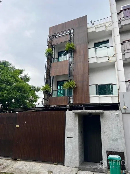 Townhouse for rent in Phaya Thai, Bangkok - Close view of the townhouse exterior with modern wood panels and a secure sliding gate.