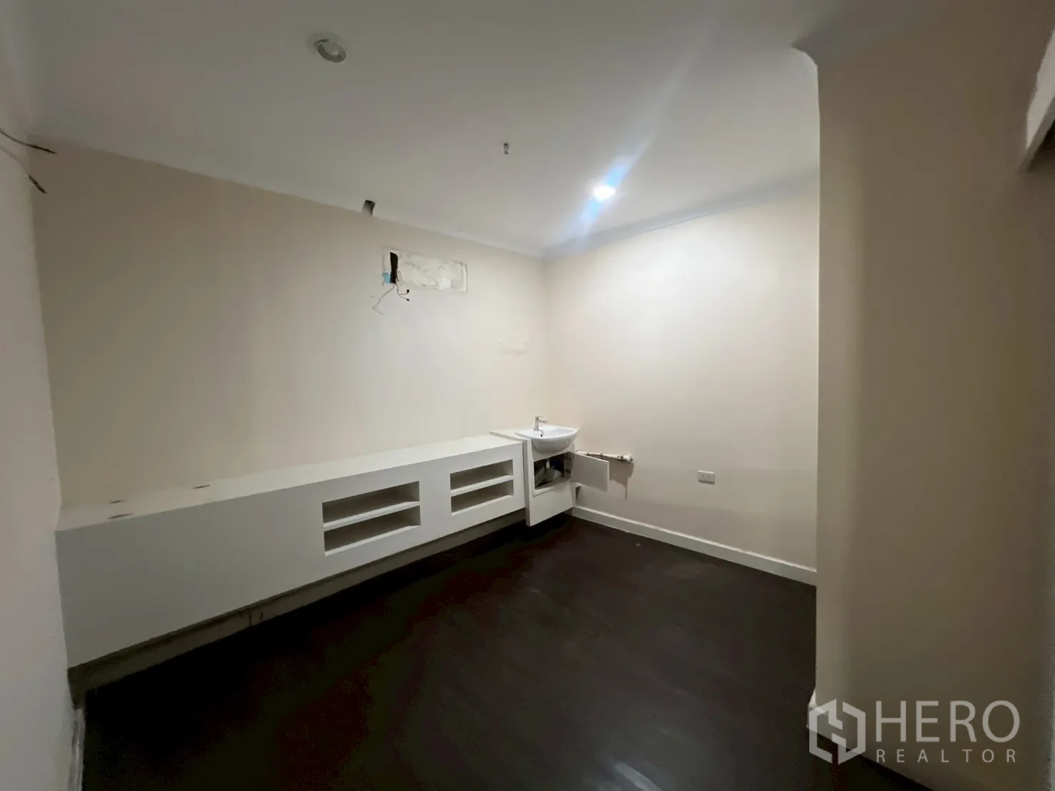 Office Space for rent in Watthana, Bangkok - Compact room with dark flooring, beige walls and extended white built-in counter with sink.