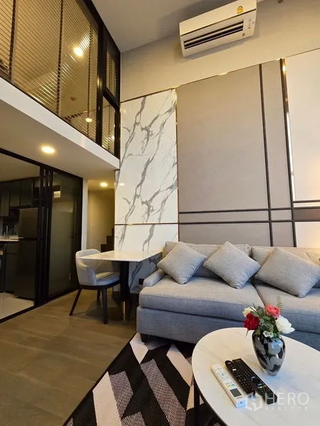 公寓 出租 - 客厅配沙发、大理石装饰墙和用餐角，层高通透