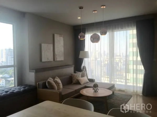 คอนโด ให้เช่าในWatthana, Bangkok - ห้องนั่งเล่นสว่าง โซฟาเข้ามุม โต๊ะกลาง โคมเพดาน และหน้าต่างสูงเต็มบานมองเห็นวิวเมือง