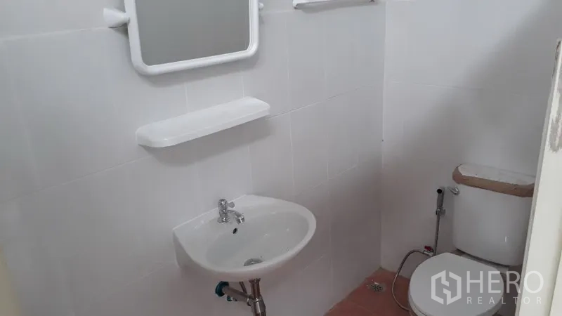 货栈 出租在Lam Luk Ka, Pathum Thani - 仓库内洁净瓷砖卫生间，配洗手盆、镜子、置物架和坐便器带喷枪。