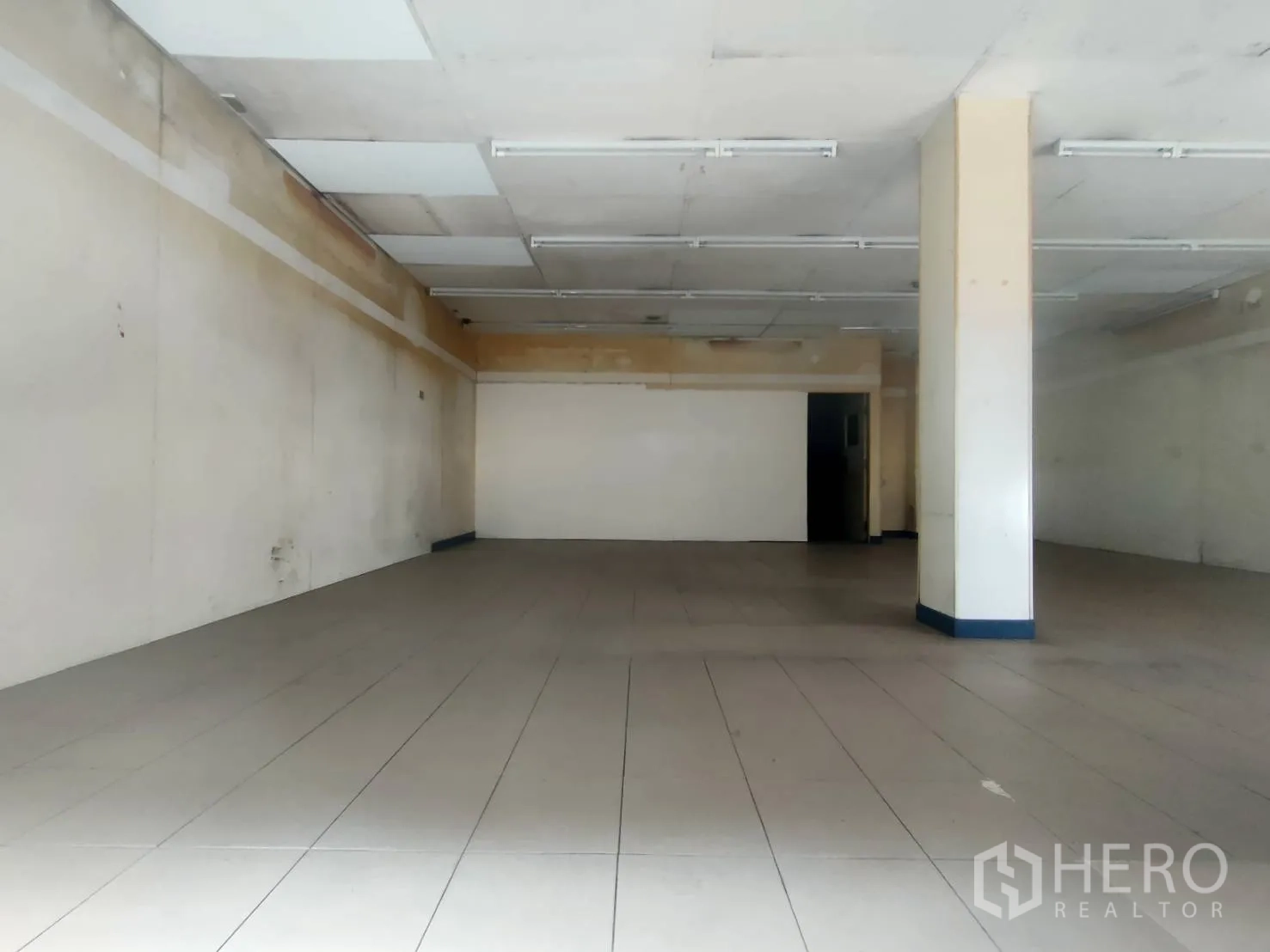 零售空间 出租在Khlong Toei, Bangkok - 宽敞空置的店铺空间，中央立柱与吊顶板，地面铺设瓷砖。