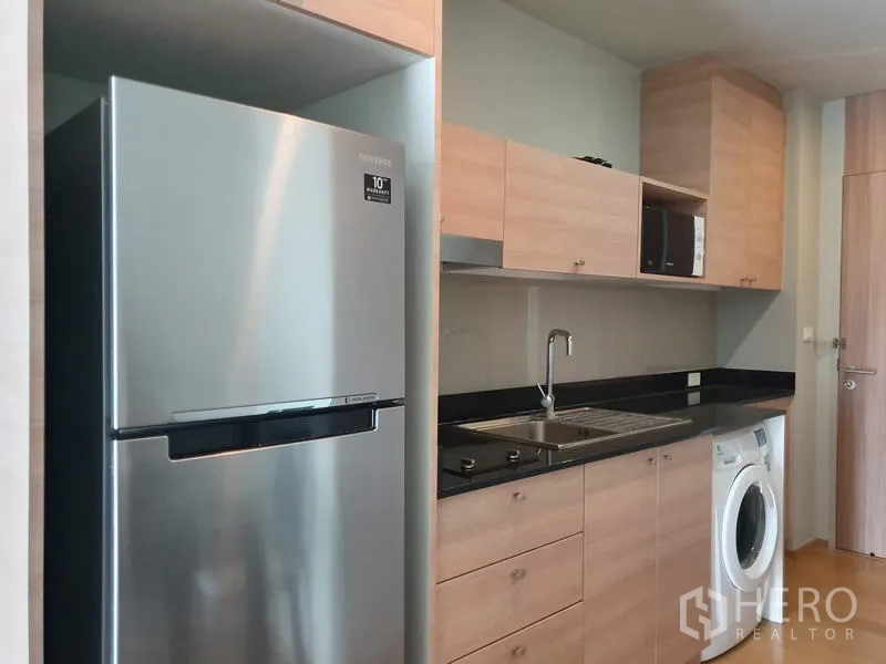 公寓 出租在Ratchathewi, Bangkok - 现代长廊式厨房，配冰箱、灶台、微波炉和洗衣机。