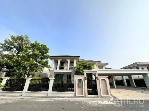 บ้าน ให้เช่าหรือขายในLat Krabang, Bangkok - ภาพภายนอกบ้านเดี่ยวสองชั้น รั้วรอบขอบชิด โรงจอดรถ และต้นไม้ใหญ่