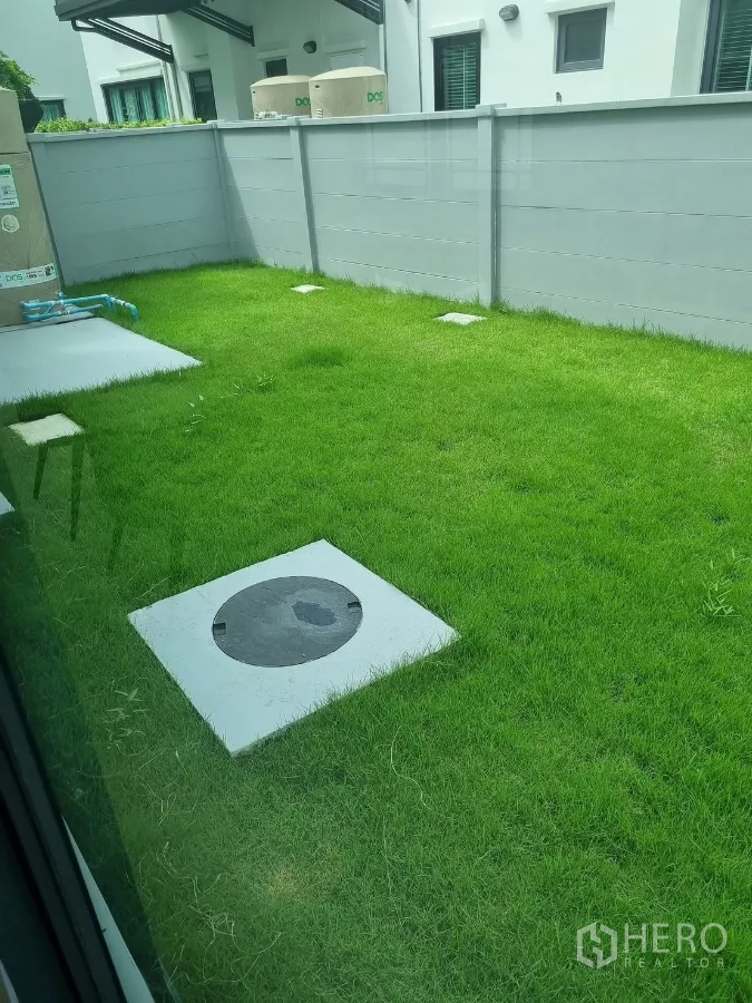 Detached House for rent in Bang Phli, Samut Prakan - Green lawn with utility access cover and boundary fence in the side yard.