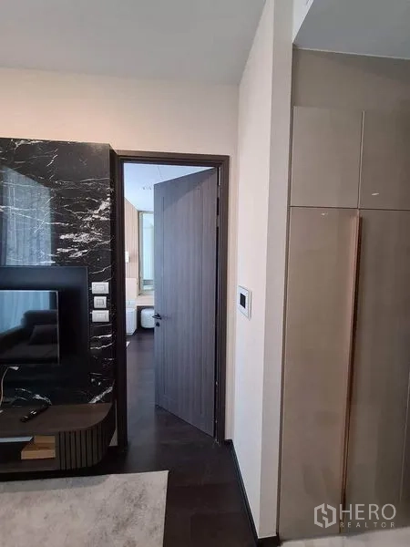 Condominium for rent in Watthana, Bangkok - Entry corridor showing marble TV wall, wooden door, and built-in closet.