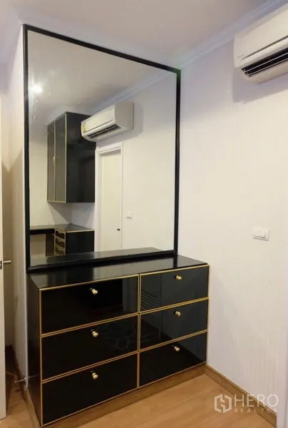 Detached House for rent in Suan Luang, Bangkok - Dressing area featuring a large mirror, black-and-gold chest of drawers, and wall-mounted air conditioner.
