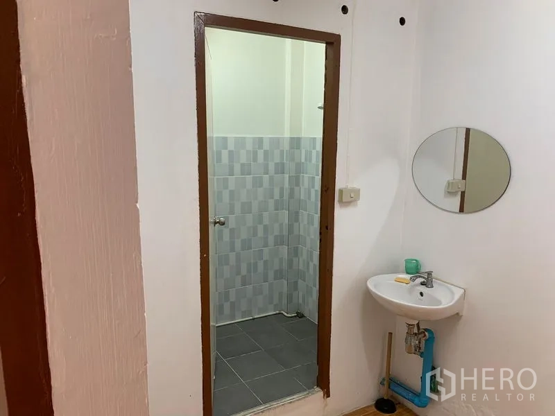 办公空间 出租在Chatuchak, Bangkok - 卫生间，瓷砖淋浴区与带镜子的洗手盆。