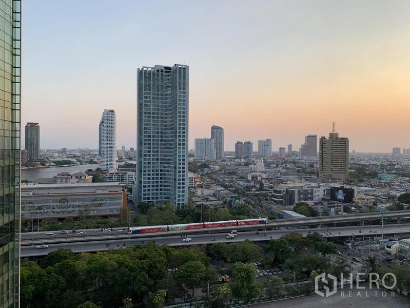 Condominium for rent or sale in Khlong San, Bangkok - Sunset skyline over Khlong San with Chao Phraya River, towers and expressway in view.