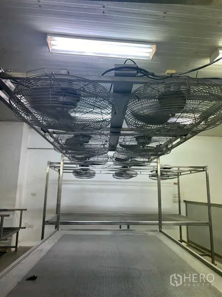 Warehouse for rent in Sam Phran, Nakhon Pathom - Row of industrial ceiling fans above metal racks for ventilation.