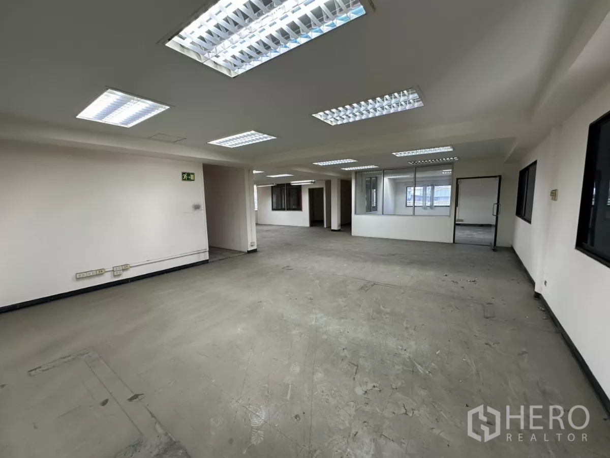Warehouse for rent in Suan Luang, Bangkok - Generous office space with suspended ceiling lights, interior windows, and neutral walls.