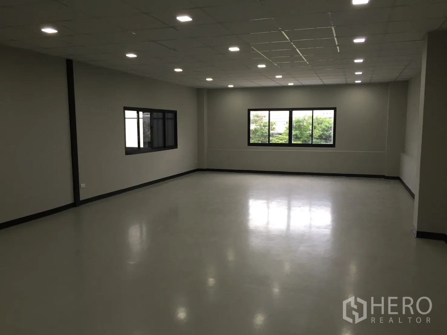 Warehouse for rent in Bang Phli, Samut Prakan - Bright open office space with ceiling lights and wide windows facing greenery.