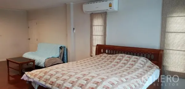 บ้าน ให้เช่าในPhra Khanong, Bangkok - ห้องนอนกว้าง เตียงไม้ ผ้าห่มลายตาราง แอร์ผนัง โซฟาและโต๊ะเล็ก ข้างหน้าต่างพร้อมผ้าม่าน