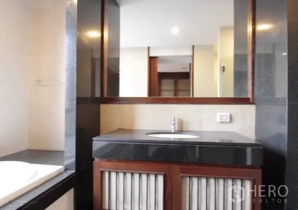 บ้าน ให้เช่าในKhlong Toei, Bangkok - ห้องน้ำสไตล์โมเดิร์น กระจกบานใหญ่ ท็อปหินสีเข้ม และตู้ลิ้นชักไม้