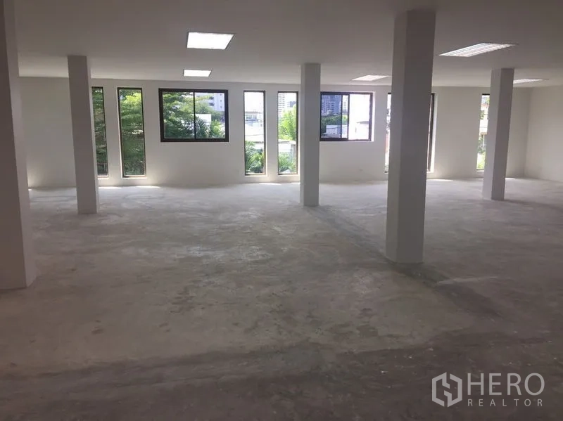 Home Office for rent in Watthana, Bangkok - Open-plan level with tall windows and city views over Thonglor greenery.