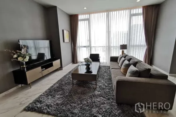 คอนโด ให้เช่าหรือขายในWatthana, Bangkok - มุมนั่งดูทีวี โซฟาสีเทา โต๊ะกลาง และหน้าต่างสูงจรดเพดาน