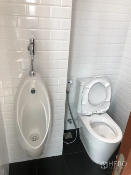 Townhouse for rent in Din Daeng, Bangkok - Clean bathroom with white subway tiles featuring a toilet and urinal.