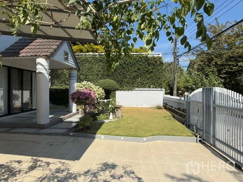 Detached House for rent in Bang Kapi, Bangkok - Front garden with lawn, flowers, white fence and covered porch.