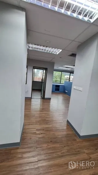 Office Space for rent in Watthana, Bangkok - Open-plan layout with grid lighting, blue storage wall and multiple windows.